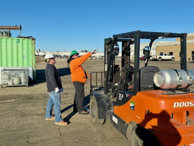 Two people standing next to a forklift